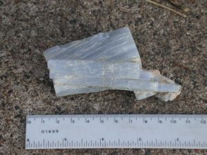 Mineral sample is shown with a ruler for scale on the bottom of the image. The sample is approximately 10cm in length.
