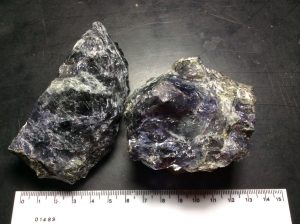 Two chunks of purple cordierite positioned side-by-side with a ruler below them for scale. Total width is 13.5cm.