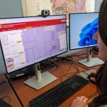 Amy sits at a desktop computer, browsing the WGNHS Mapping Status Portal
