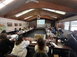 Roomful of workshop participants watching a woman presenting.